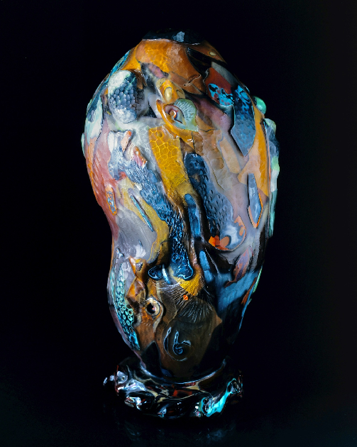 A vase with blue, yellow and orange paint on it.