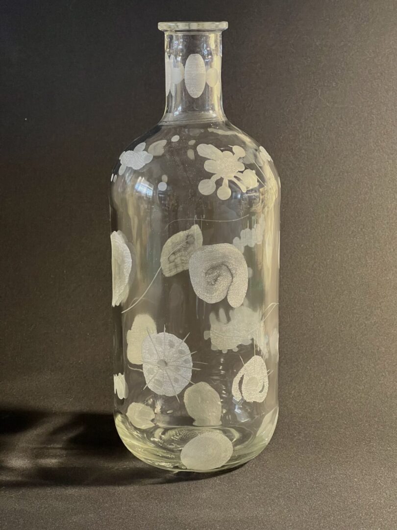 A glass bottle with white flowers on it.